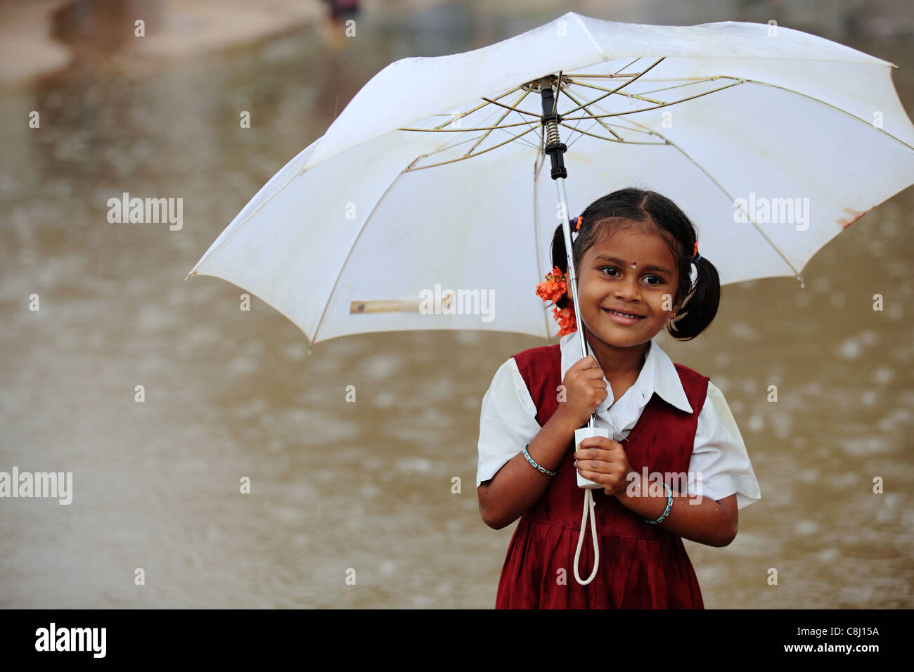 Schulkind unter dem Regen mit Regenschirm Andhra Pradesh in Indien Stockfoto