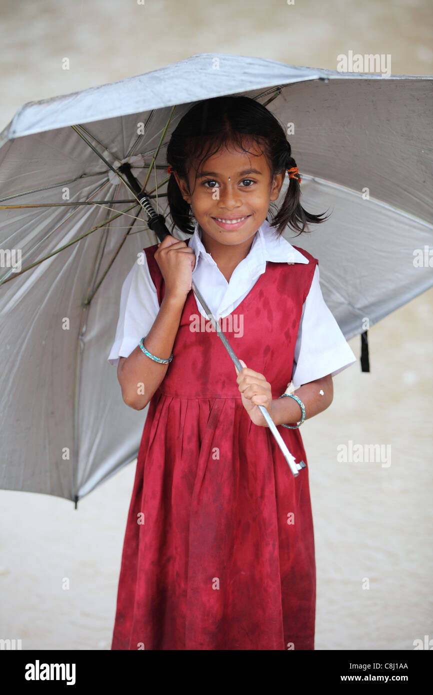 Schulkind unter dem Regen mit Regenschirm Andhra Pradesh in Indien Stockfoto
