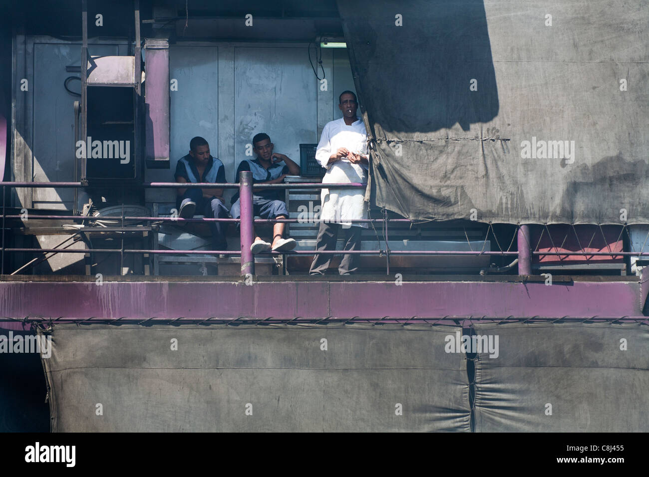 Nahaufnahme der drei Besatzungsmitglieder des Nil-Kreuzfahrt-Schiff sitzen in der rauchigen Dämpfe in das Heck des Schiffes, eine Rauchen einer Zigarette Stockfoto