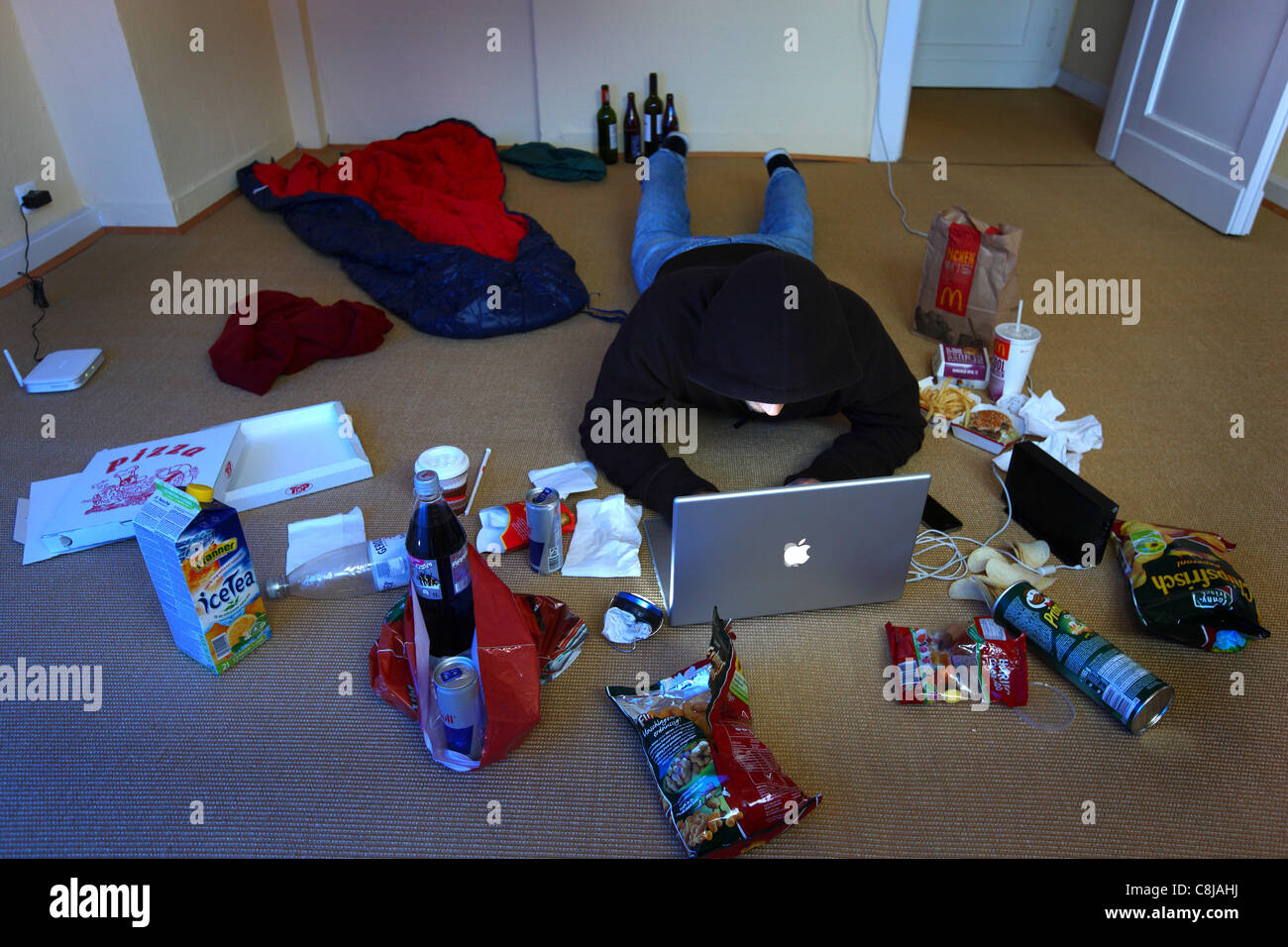 Computer-Benutzer, Hacker, verschwörerisch, sitzt in einer leeren Wohnung, mit einem Laptop. Symbolbild, Computer-Internet-Kriminalität. Stockfoto