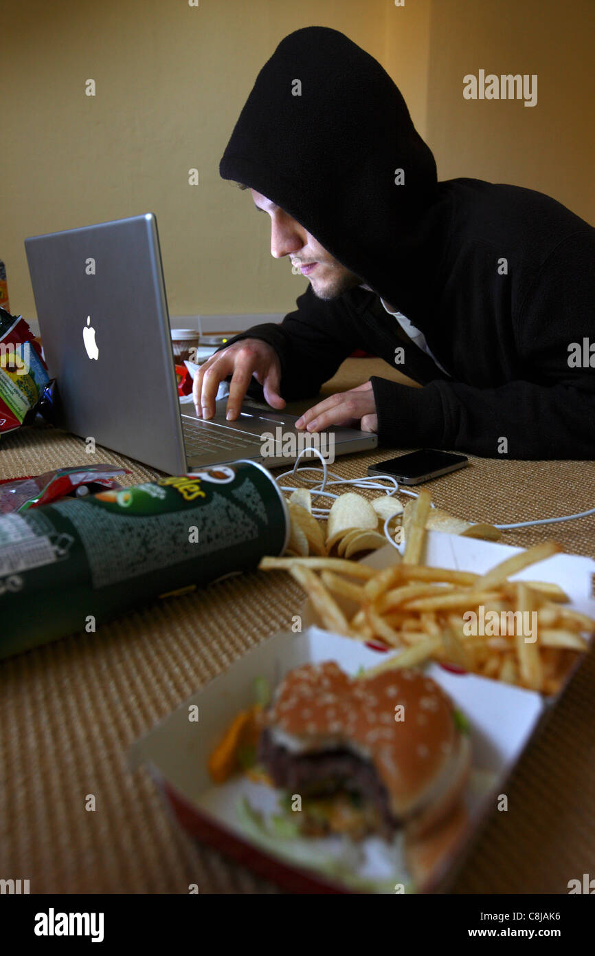Computer-Benutzer, Hacker, verschwörerisch, sitzt in einer leeren Wohnung, mit einem Laptop. Symbolbild, Computer-Internet-Kriminalität. Stockfoto
