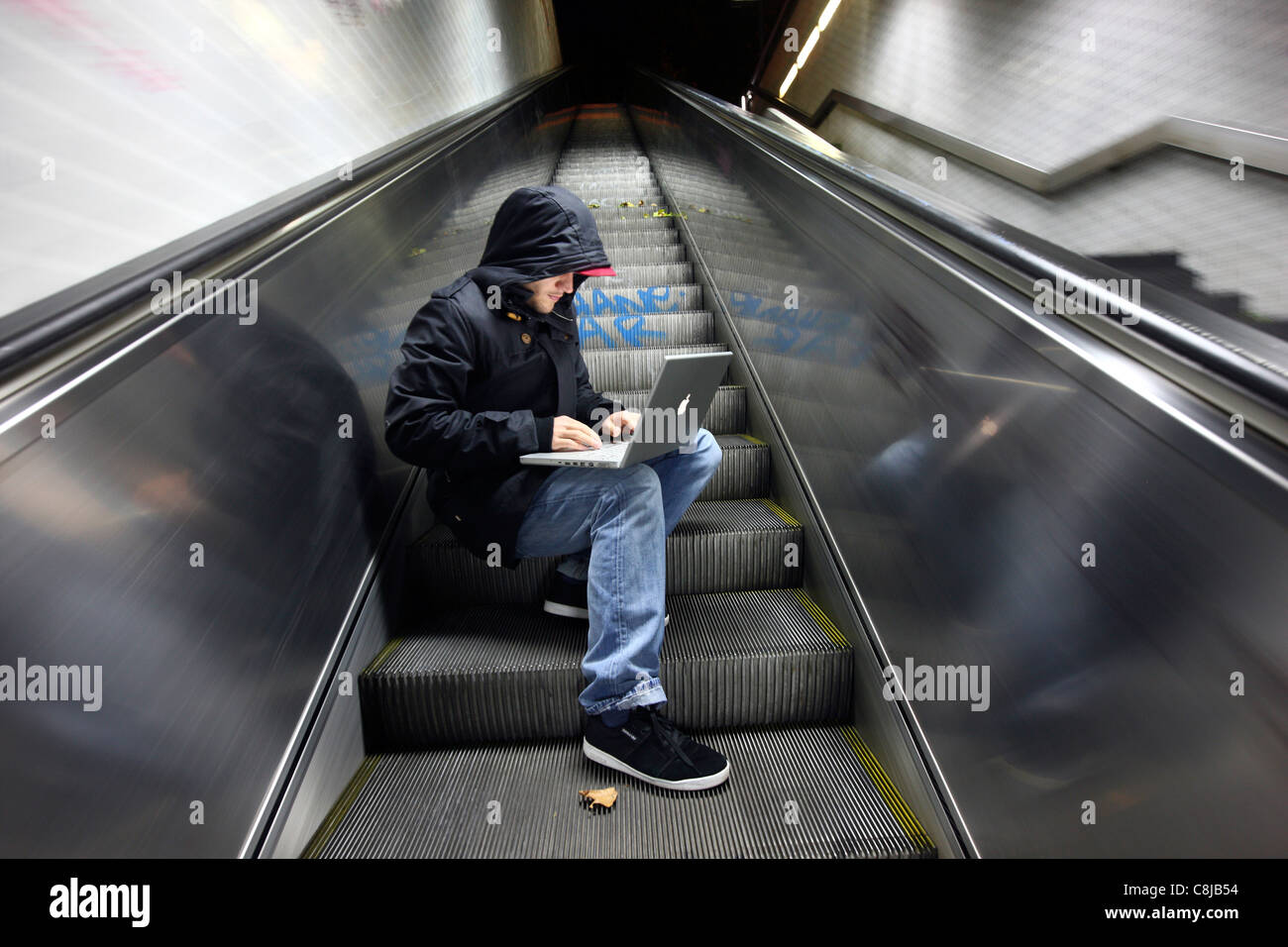 Computer-Benutzer, Hacker, verschwörerisch sitzt mit einem Laptop in einer u-Bahn-Station. Symbolbild, Computer-Internet-Kriminalität. Stockfoto