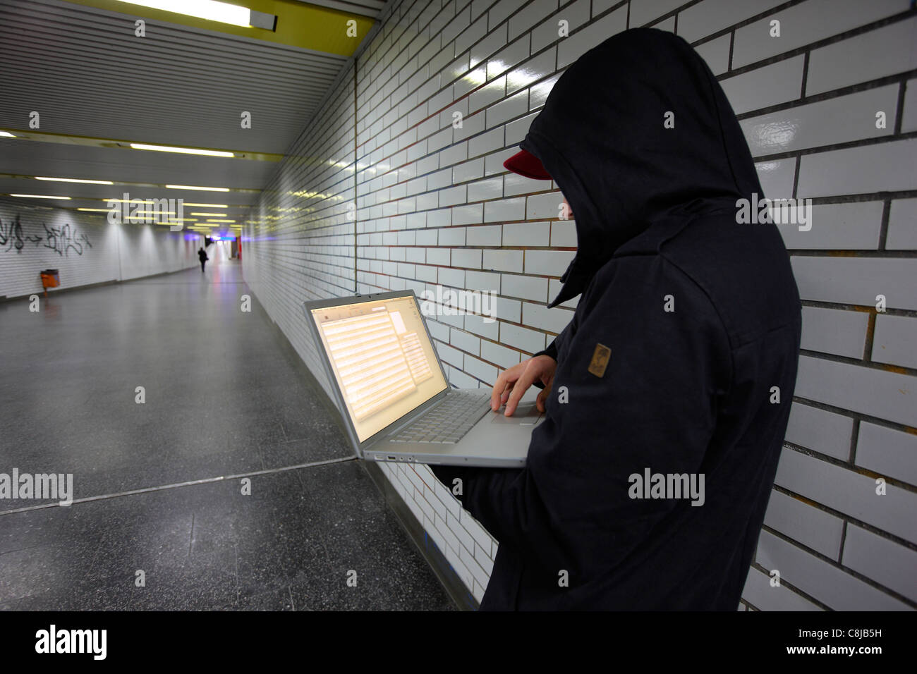 Computer-Benutzer, Hacker, verschwörerisch sitzt mit einem Laptop in einer u-Bahn-Station. Symbolbild, Computer-Internet-Kriminalität. Stockfoto