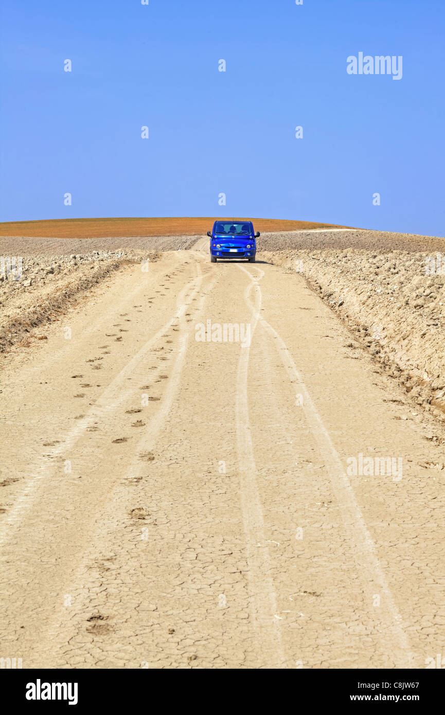 ein blaues Auto inmitten von den abgeernteten Feldern der Toskana Stockfoto