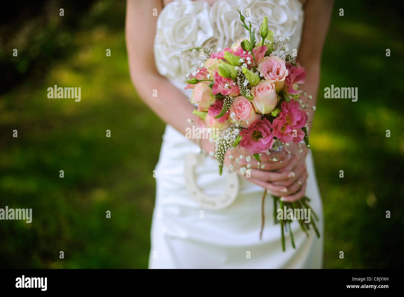 eine Braut hält einen bunten Blumenstrauß an ihrem Hochzeitstag Stockfoto