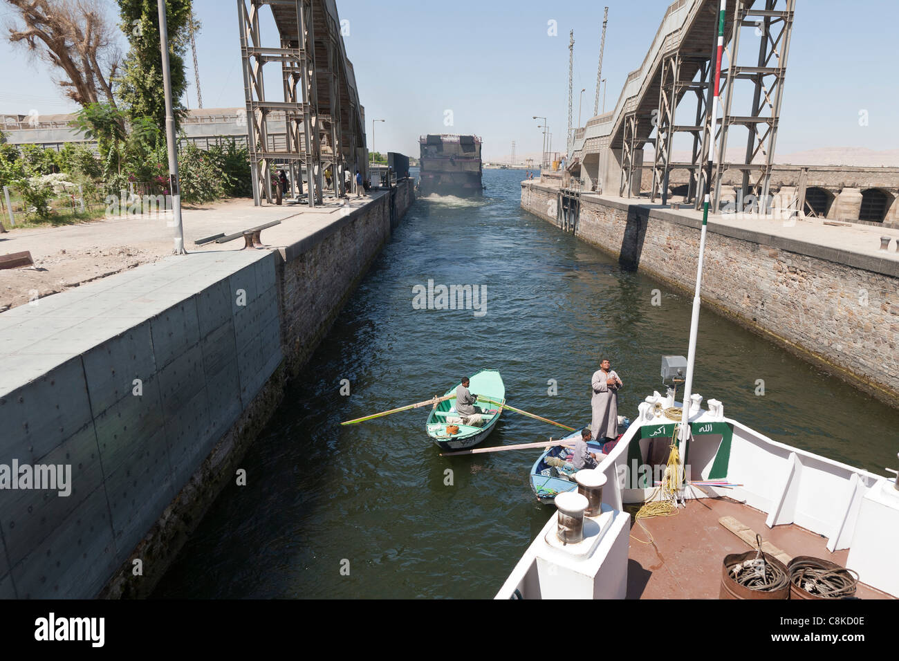 Der Bug des Nil Cruiser nach anderen durch Esna Schleuse Ägypten mit Markt Händler zwischen den beiden kleinen Ruderboot Stockfoto