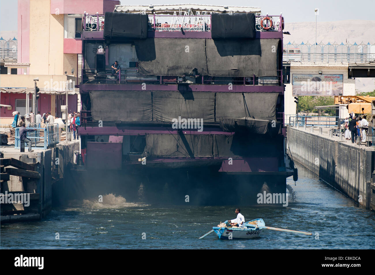 Rauchen verschmutzten Heck eine Nil Kreuzfahrt Boot vorbei durch Esna Schleuse Ägypten mit einem kleinen Ruderboot hinter Markt-Händler Stockfoto