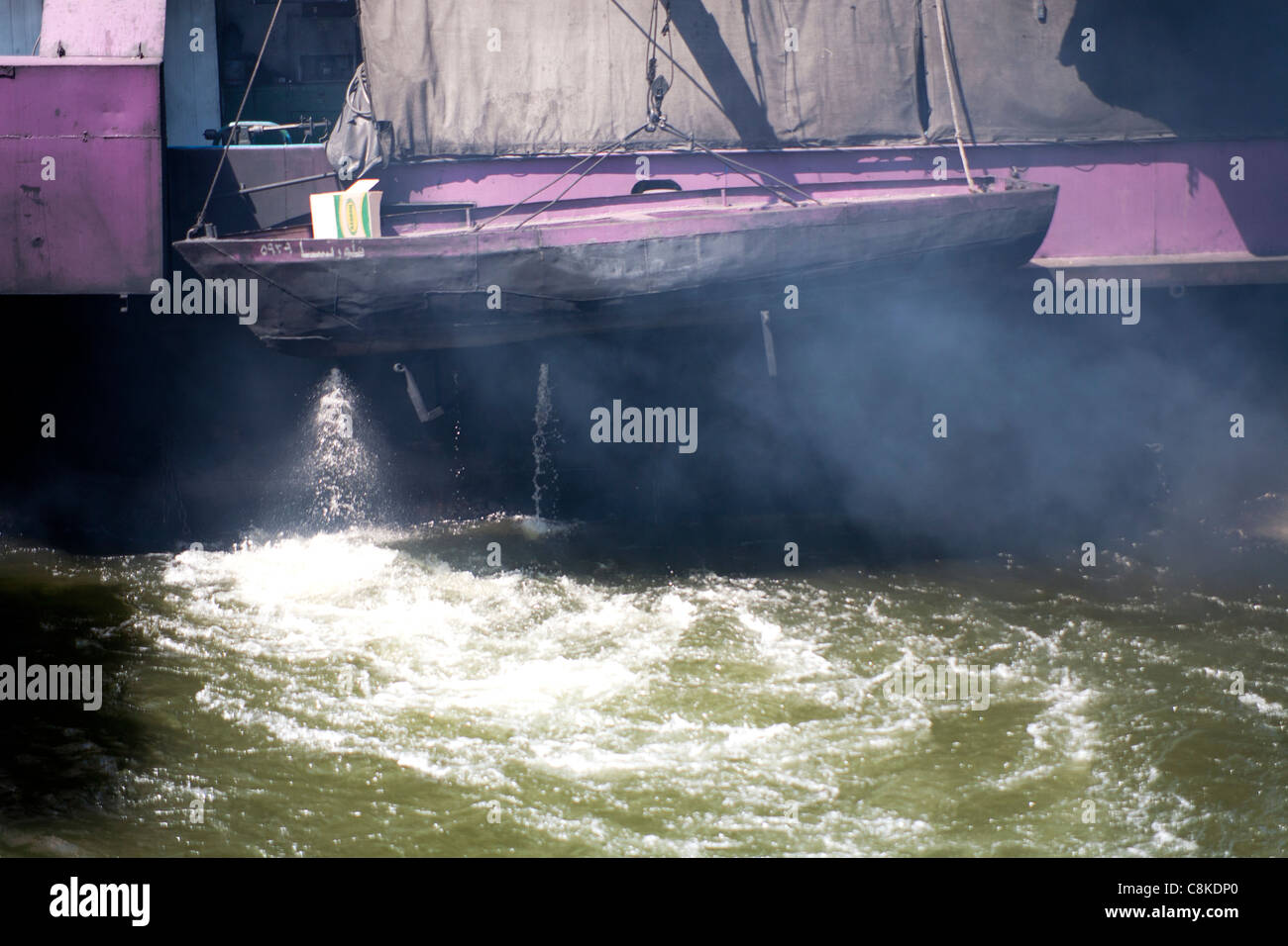 Kleine Holzboot, gebunden an das Heck des Rauchens Heck Nils eine Nil Kreuzfahrt Boot navigieren Esna Schleuse Ägypten Stockfoto