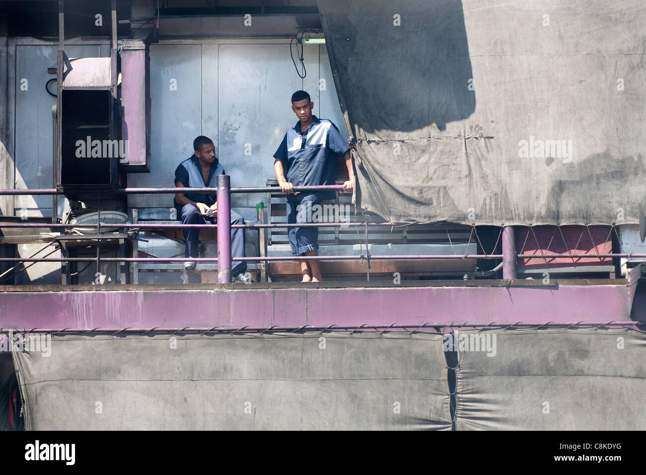 Zwei Besatzungsmitglieder des Nil Kreuzfahrt Boot sitzen in der rauchigen Dämpfe in das Heck des Schiffes hinter Leinwand-Folie Stockfoto
