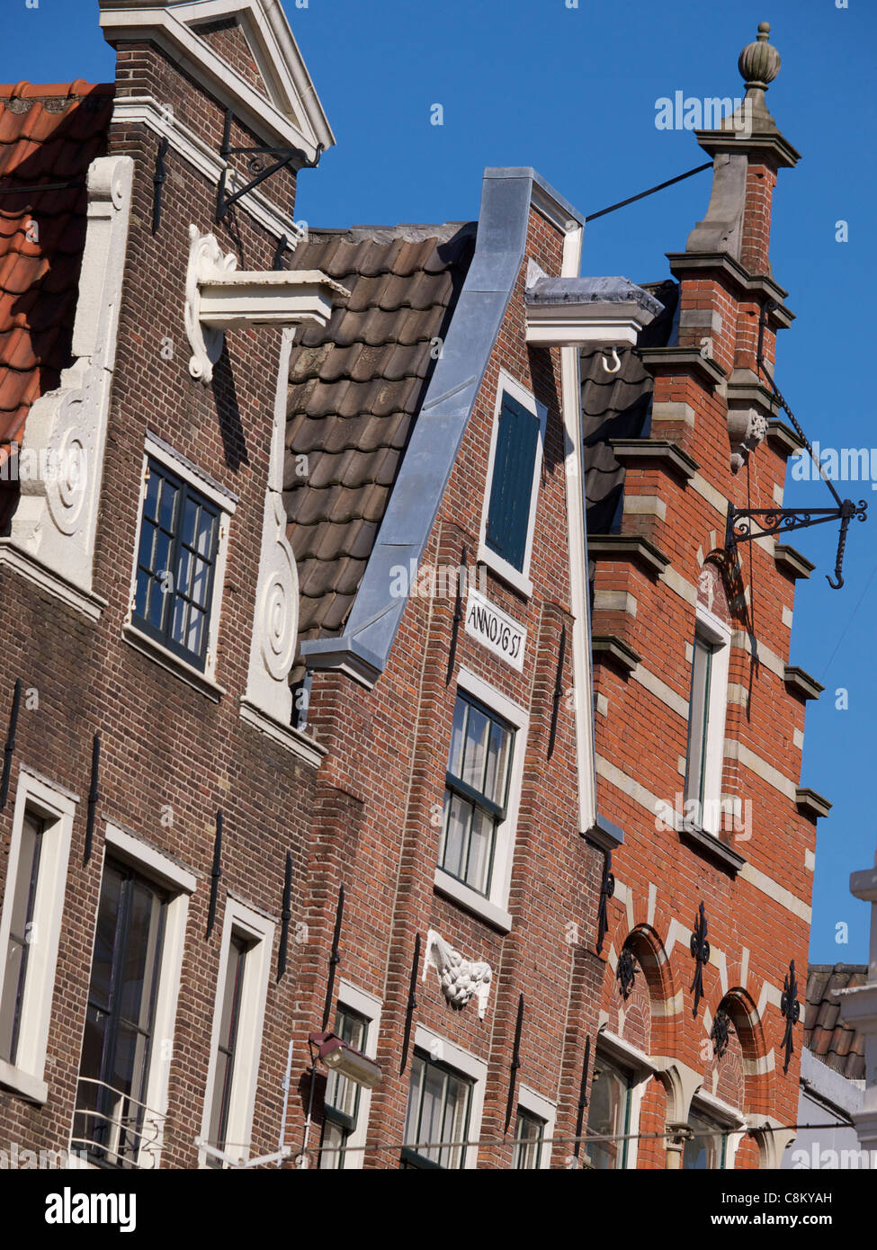 Drei historische Gebäude-Fassaden mit verschiedenen Designs, mit blauem Himmel im Hintergrund, in der Innenstadt von Amsterdam Stockfoto