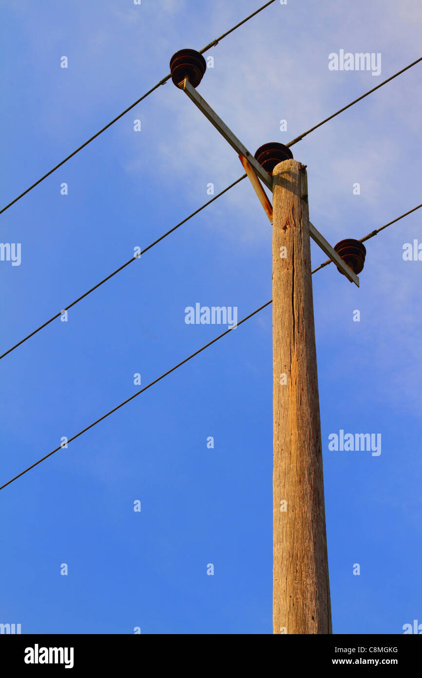 Strom Stromkabel auf hölzernen Telegrafenmast mit einem blauen Himmelshintergrund Stockfoto