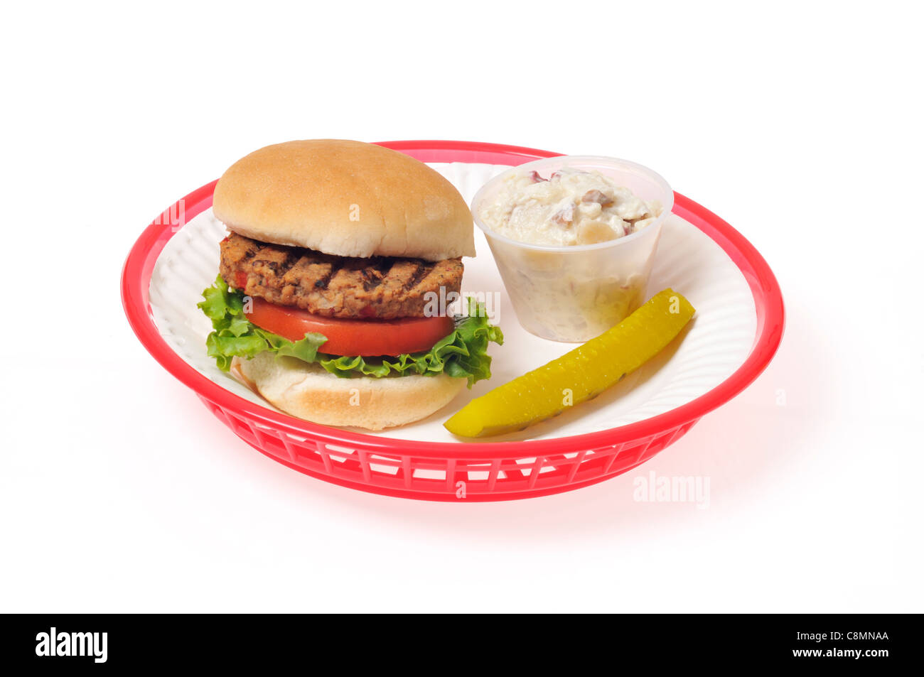 Veggie-Burger mit Salat und Tomate in Brötchen in einem roten Retro-Kunststoff-Korb auf weißem Hintergrund, gegrillte Ausschnitt. Stockfoto