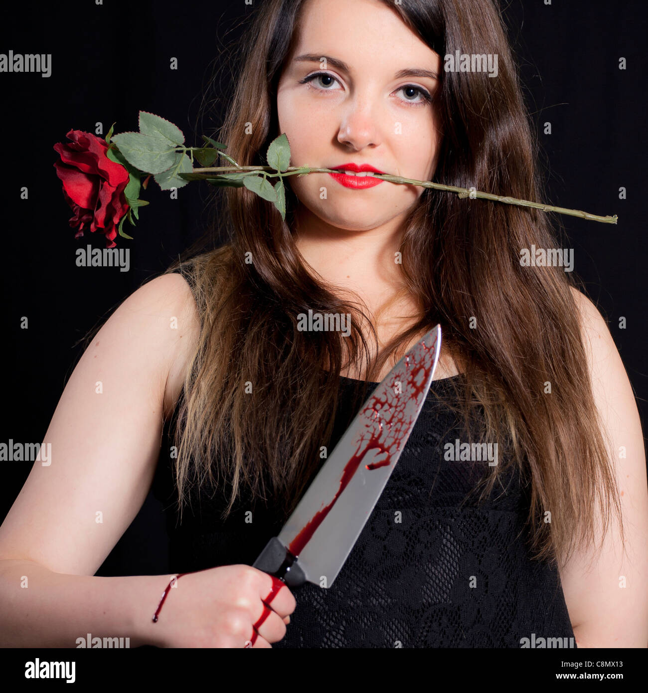 junge Frau mit einem blutigen Messer und eine rote rose Stockfoto