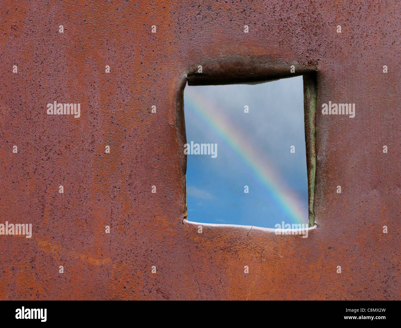 hoffe: Blick auf Regenbogen durch Loch in rostigen metallische Oberfläche Stockfoto