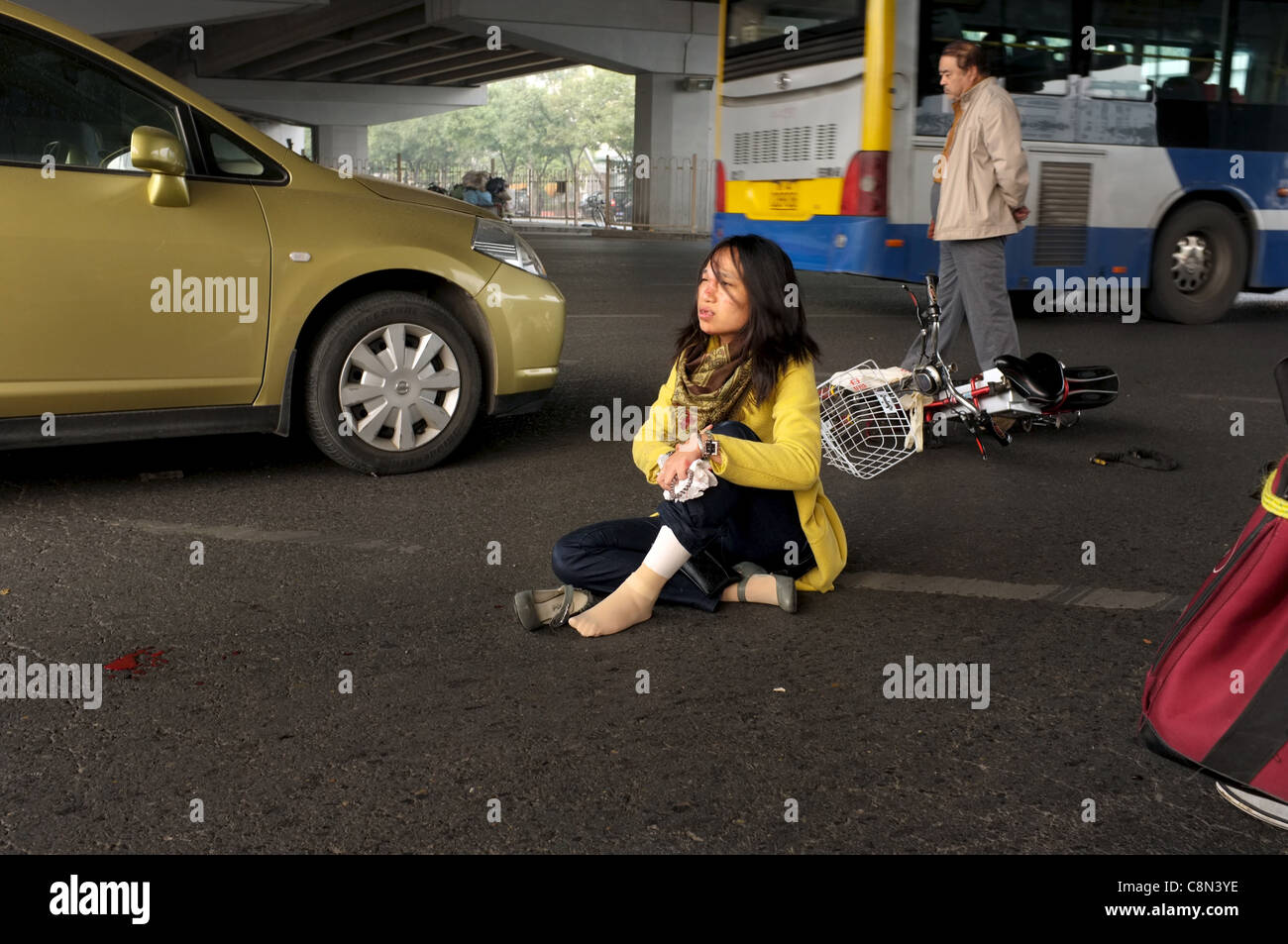 Eine Frau sitzt auf dem Boden, nachdem ihr Fahrrad bei einem Verkehrsunfall in Peking, China von einem Auto angefahren wurde. 20. Oktober 2011 Stockfoto