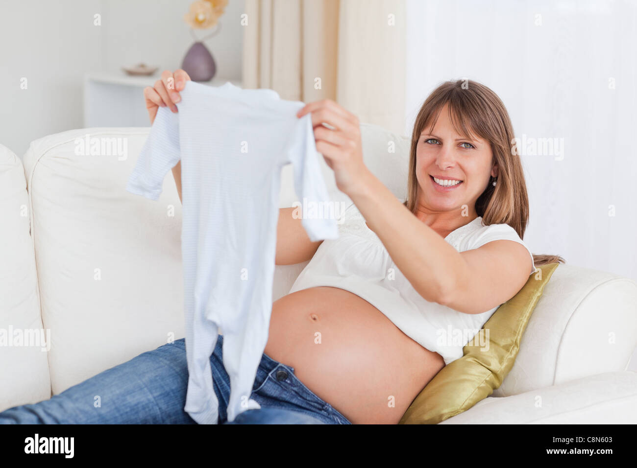 Charmante schwangere Frau mit einem Baby auf einem Sofa liegend wachsen Stockfoto
