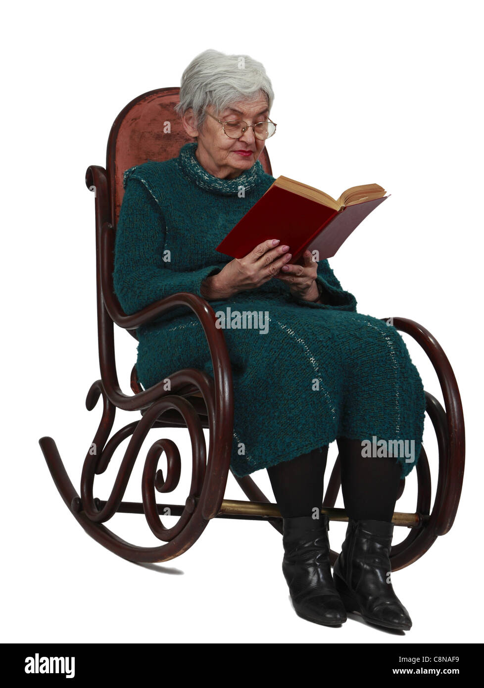 Alte Frau liest ein schwarzes Buch während der Sitzung in einer Wippe, isoliert auf einem weißen Hintergrund. Stockfoto