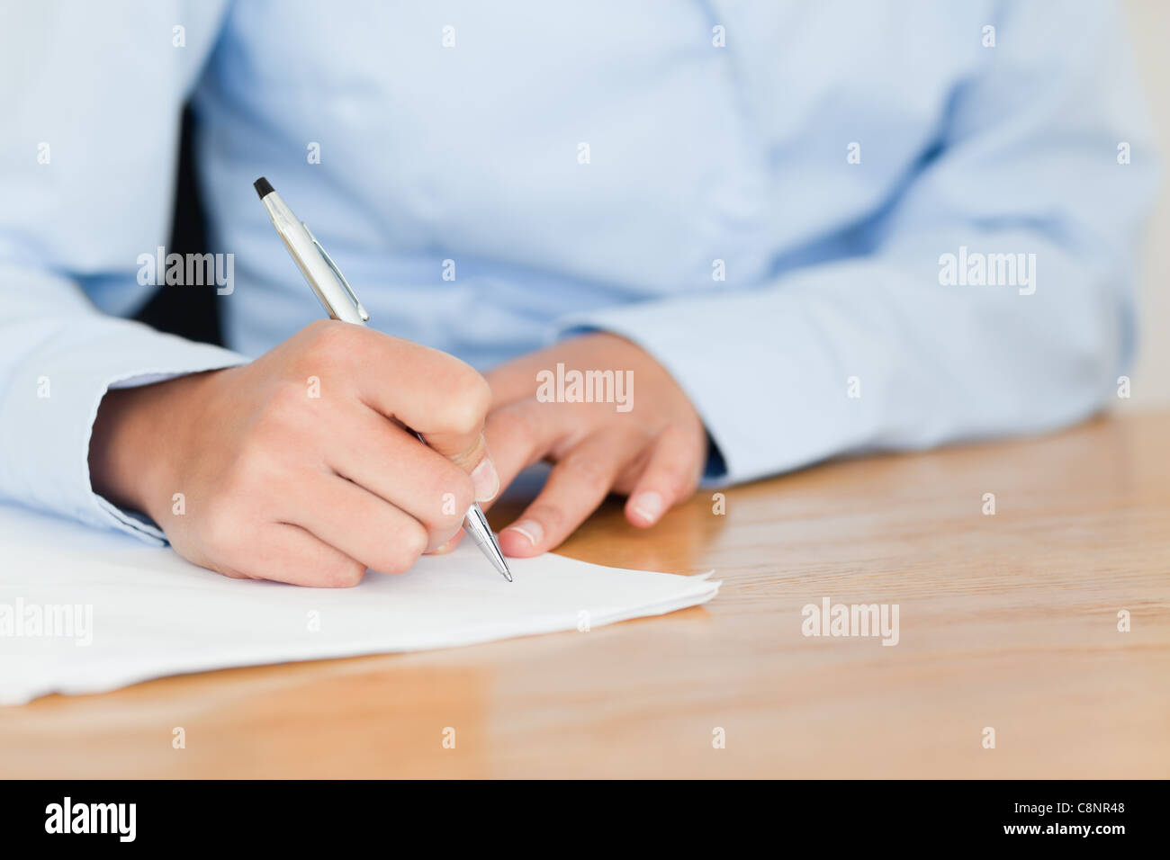 Frontalansicht einer jungen Frau, die beim Sitzen auf einem Blatt Papier zu schreiben Stockfoto