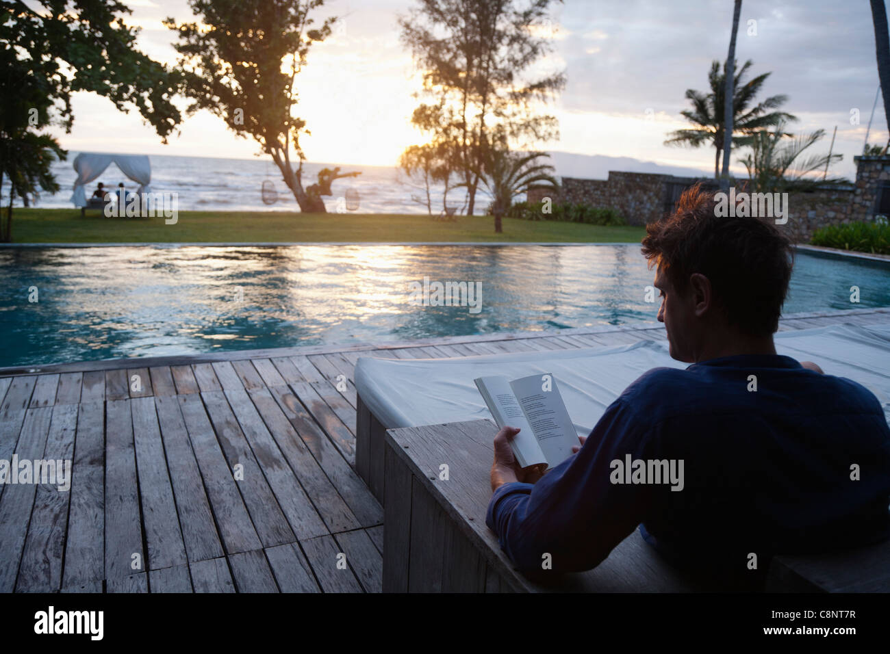 Kaukasischen Mann lesen am Pool Stockfoto