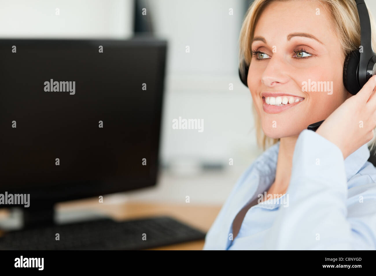 Porträt einer lächelnden Geschäftsfrau mit Kopfhörer arbeiten mit Computern, die auf der Suche an anderer Stelle Stockfoto