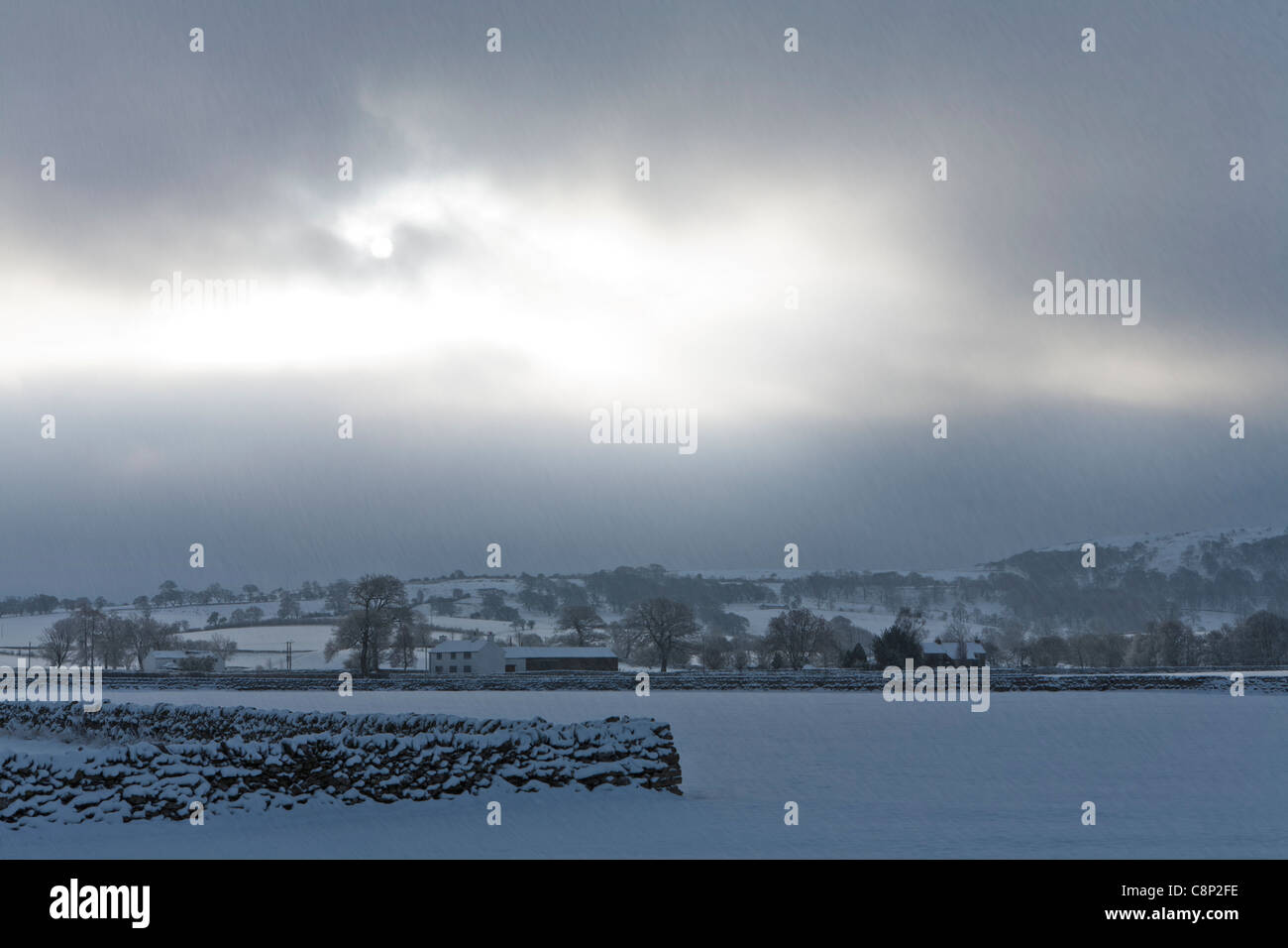 Winter-Szene in Lakeland Fells und entfernten Bauernhaus mit liegender Schnee und dunklen Himmel. Cumbria, England Stockfoto