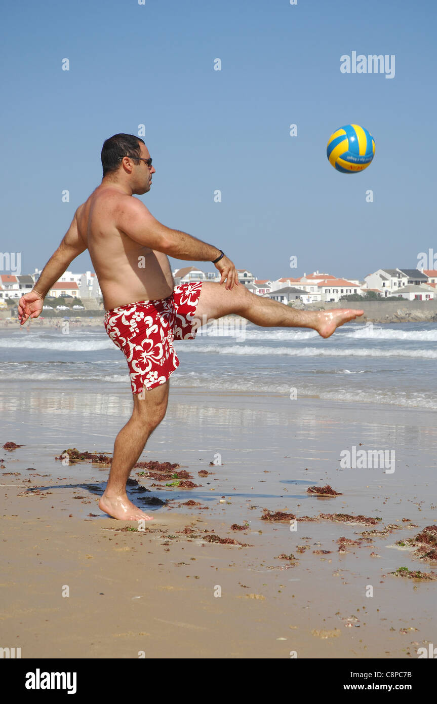 Ein dicker Mann mit einem Ball spielen am Strand Stockfoto