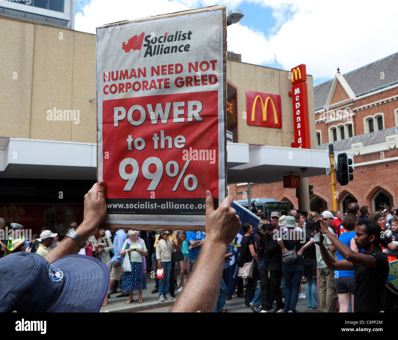 Demonstrant hält einen "Menschen brauchen nicht Corporate Gier" Banner neben einem Macdonald Zeichen. Stockfoto