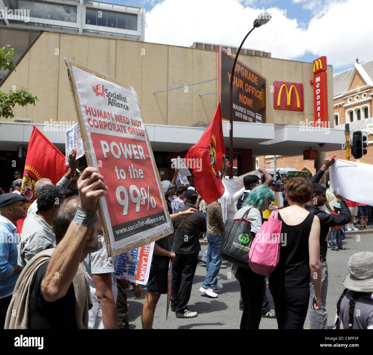 Demonstrant hält einen "Menschen brauchen nicht Corporate Gier"-Banner in der Nähe ein Macdonald Zeichen. Stockfoto