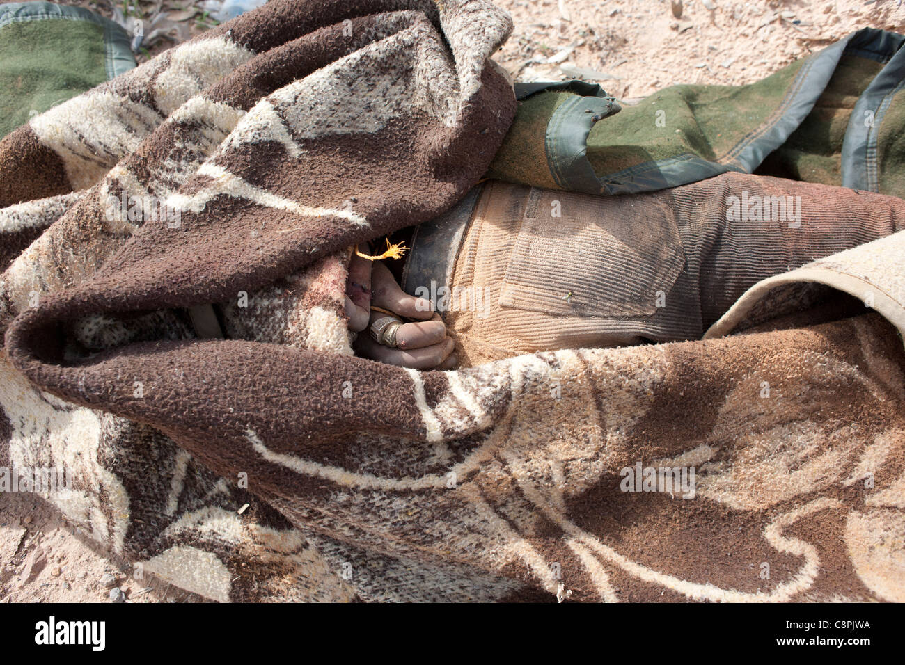 Einer der Oberst Gaddafis bewacht legt Toten in den Straßen auf Sirt nach einem NATO-Luftangriff auf Gaddafi-Konvoi. Stockfoto