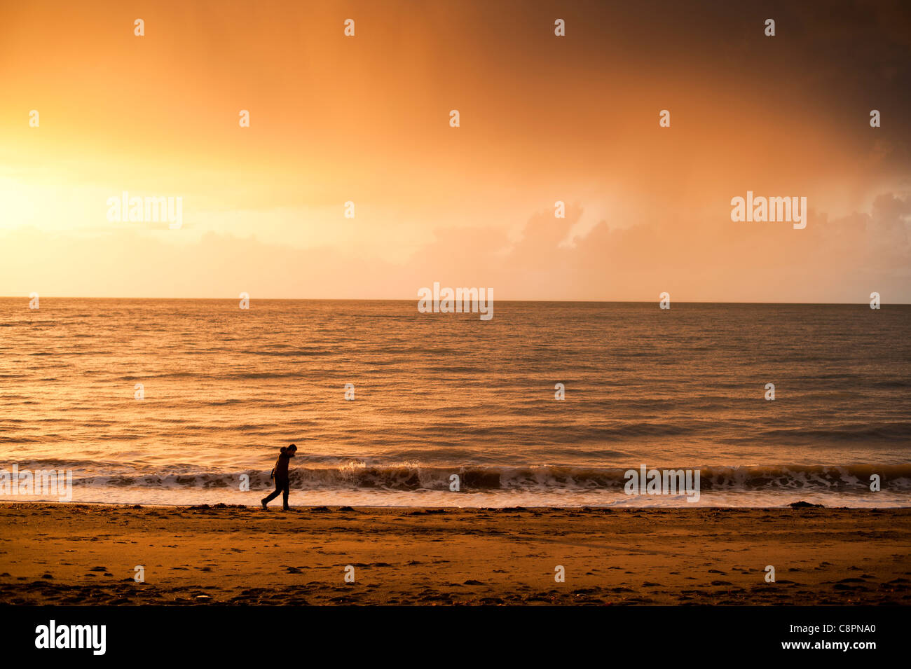 ein Mann allein zu Fuß am Strand am Ende des Tages Aberystwyth Meer, Oktober-Nachmittag, Wales UK Stockfoto