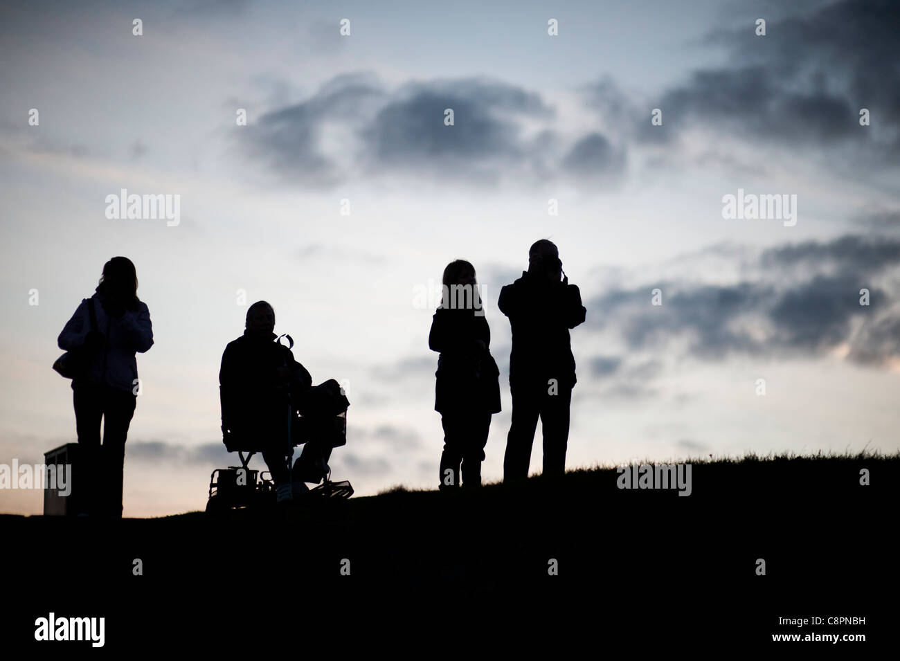 Vier Personen, in einem Rollstuhl, Silhouette gegen den Himmel, Aberystwyth in der Abenddämmerung, Oktober 2011, Wales UK Stockfoto