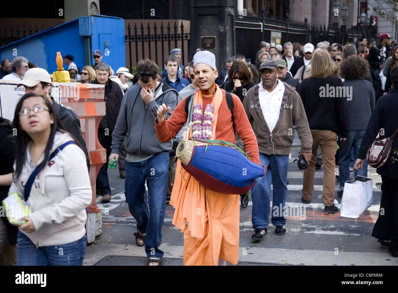 Freudige Hari Krishna-Anhänger geht und spielt seine Trommel am Broadway im Bankenviertel in New York City Stockfoto