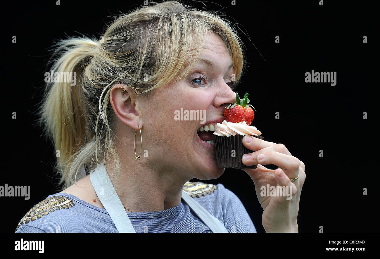 Starkoch und Kochbuchautorin Rachel Allen abgebildeten Essen einen Cupcake vor einem schwarzen Hintergrund. Stockfoto