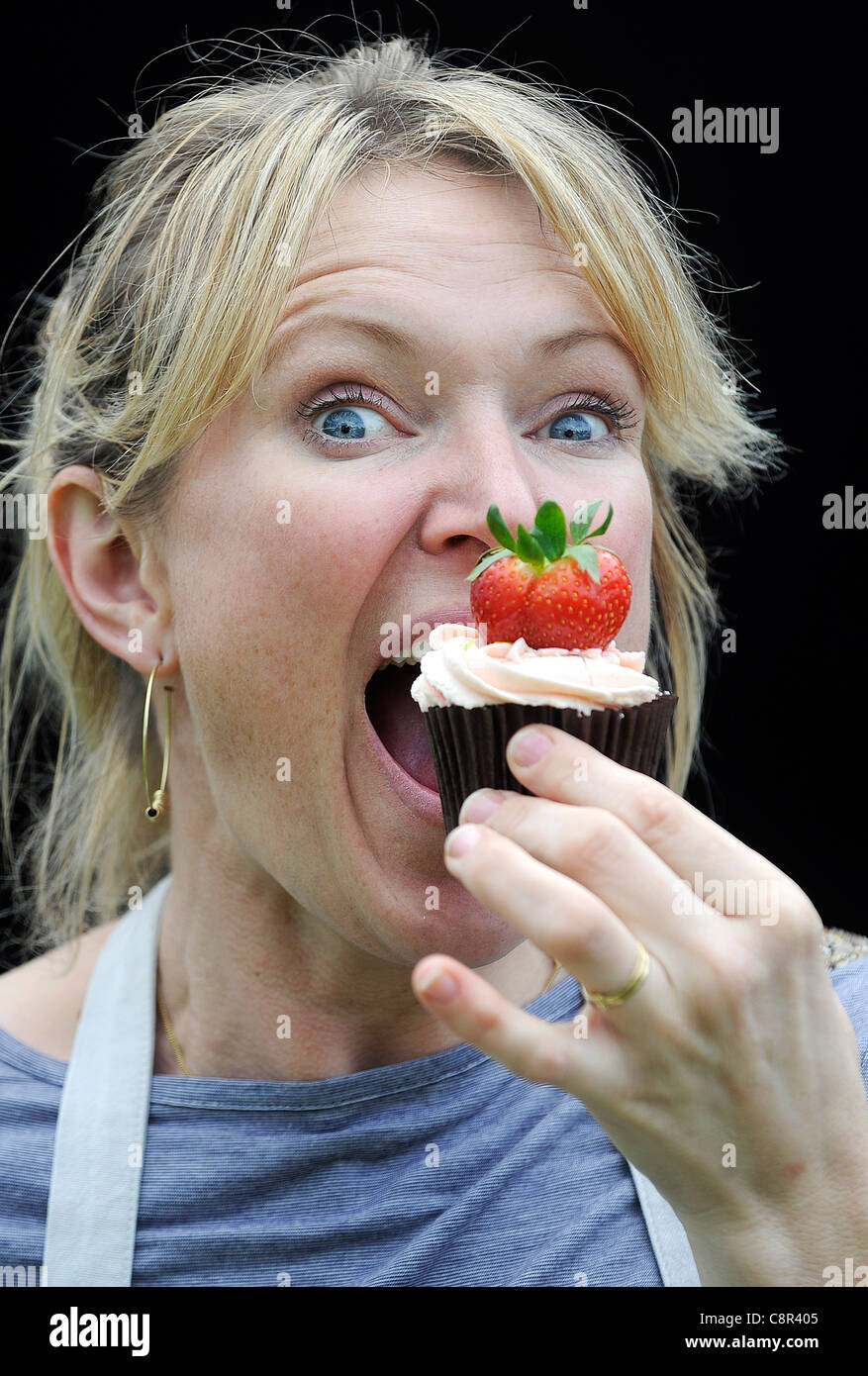 Starkoch und Kochbuchautorin Rachel Allen abgebildeten Essen einen Cupcake vor einem schwarzen Hintergrund. Stockfoto