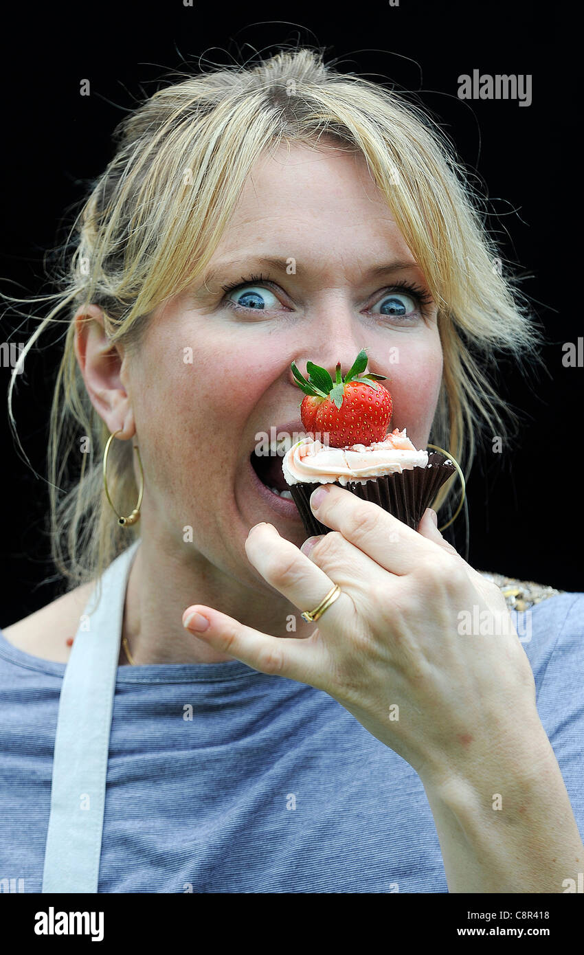 Starkoch und Kochbuchautorin Rachel Allen abgebildeten Essen einen Cupcake vor einem schwarzen Hintergrund. Stockfoto