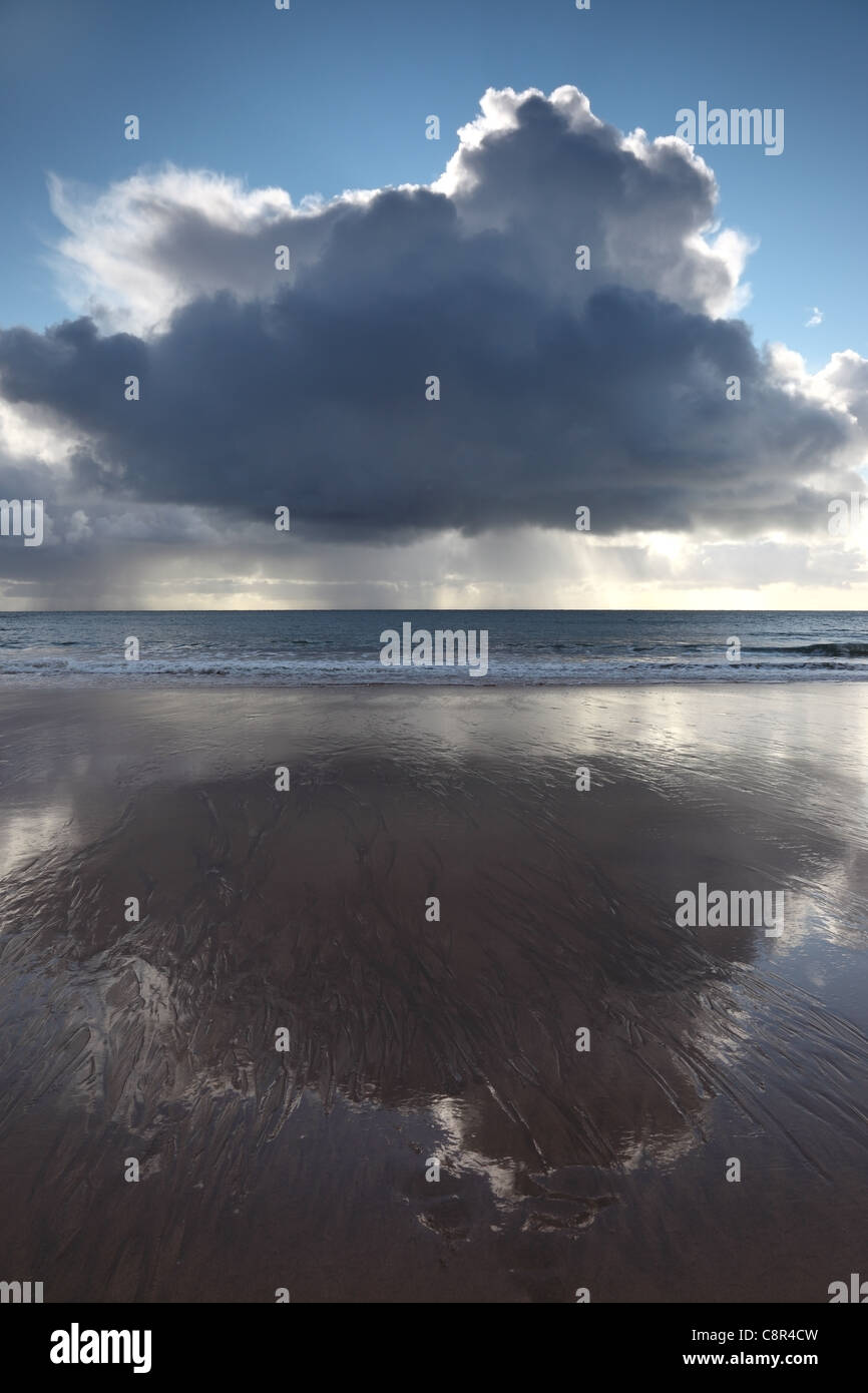 Gewitterwolken und schweren Bands von Regen über dem Meer spiegelt sich auf einem Strand Vereinigtes Königreich UK Stockfoto