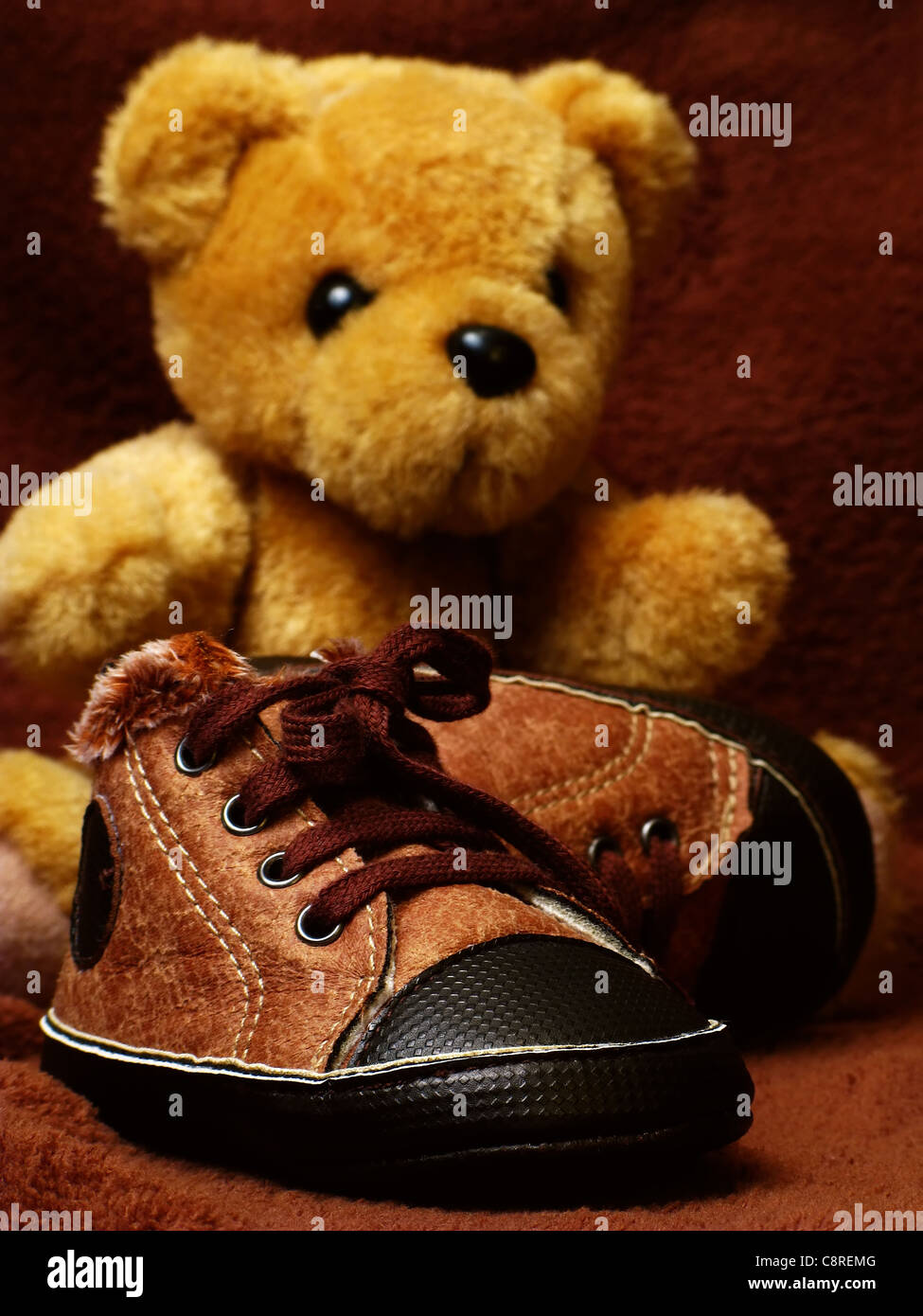 Babyschuhe mit Teddybär im Hintergrund Stockfoto