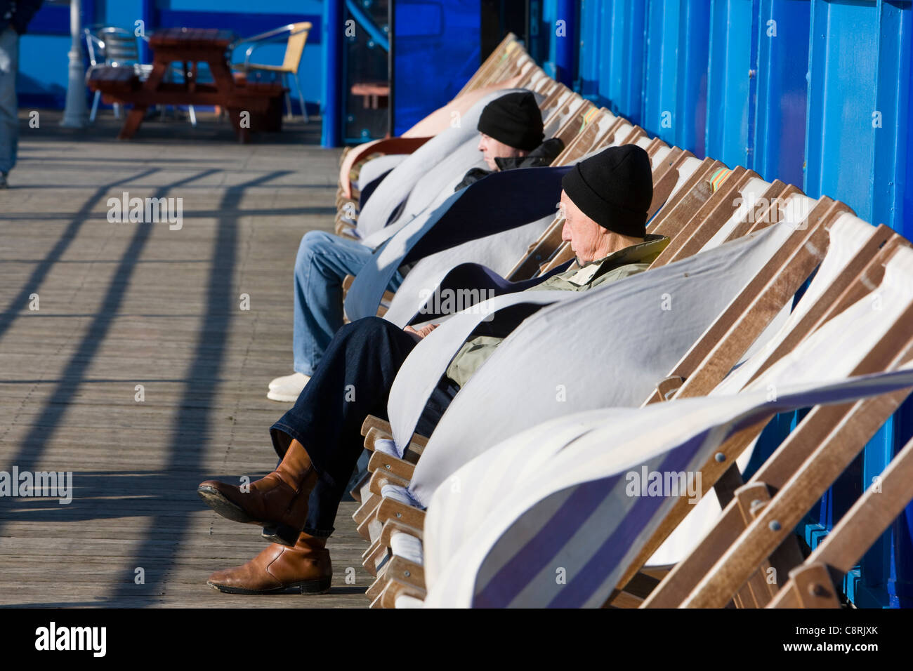Sonnenbaden in einem Liegestuhl an einem angenehm sonnig und warm, aber sehr windigen Herbsttag in Blackpool, Großbritannien Stockfoto