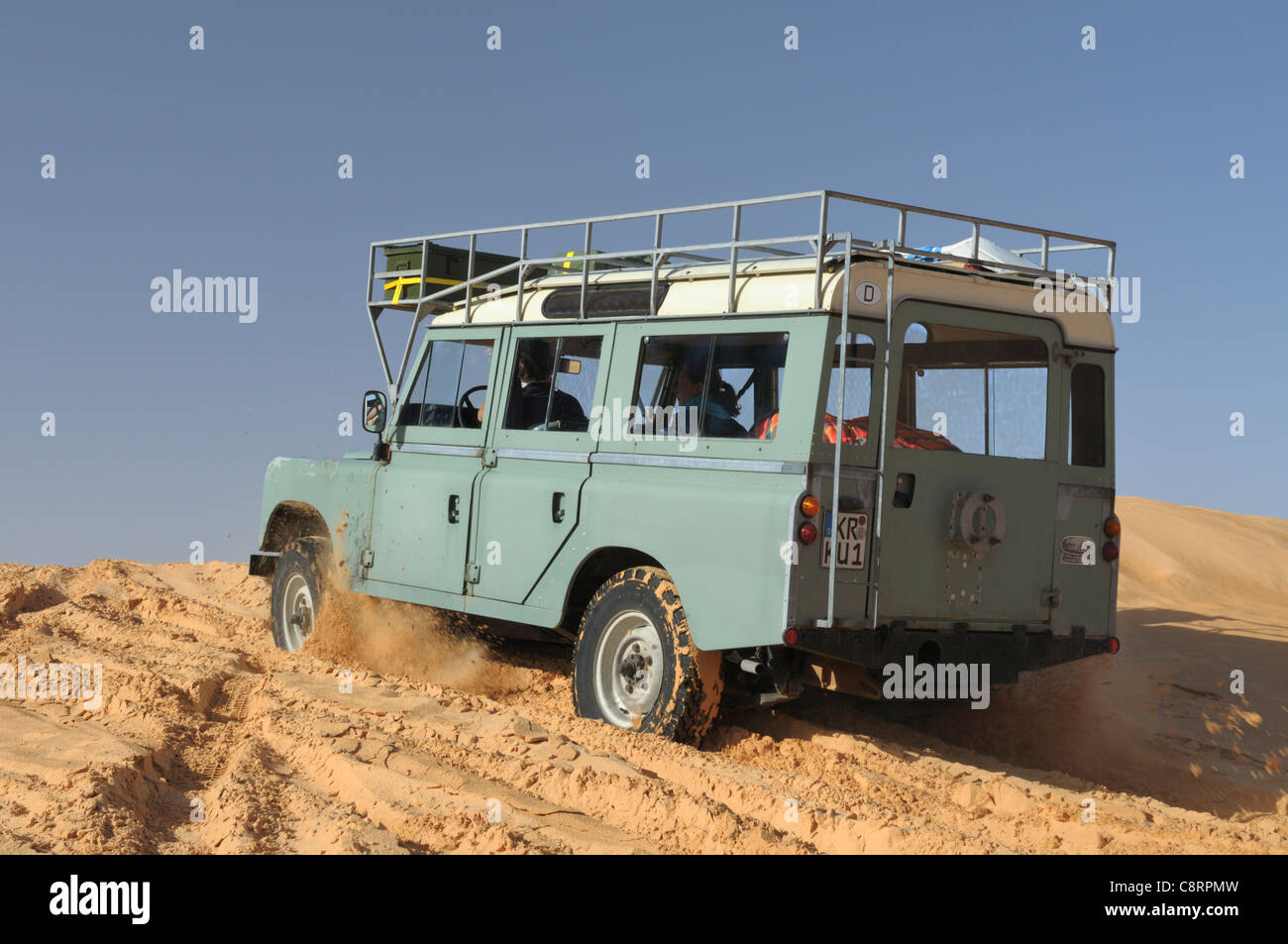 Afrika, Tunesien, nr. Tembaine. Wüste Reisende fahren ihre 1975 Land Rover Serie 3 Kombi durch eine Sandfield... Stockfoto