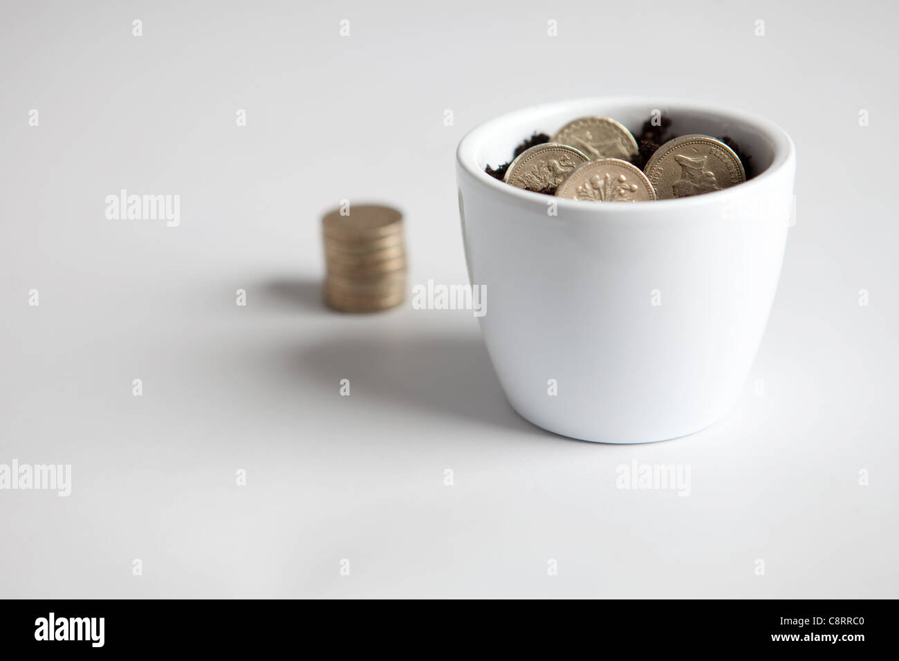 Ein Blumentopf mit Pfund-Münzen, um eine konzeptionelle Botschaft über Geld geben Stockfoto