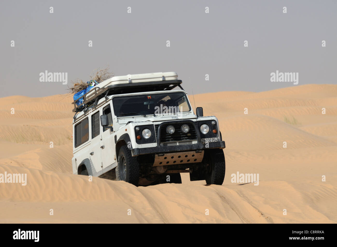 Afrika, Tunesien, nr. Tembaine. Land Rover Defender 110 TD5 Station Wagon auf seinem Weg durch eine Strecke von Sanddünen nahe... Stockfoto