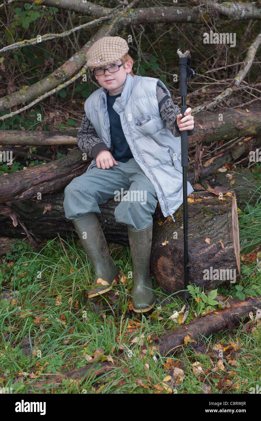 Junge Mann in die Landschaft tragen Gummistiefel und flache Kappe mit Walking Stock. Stockfoto