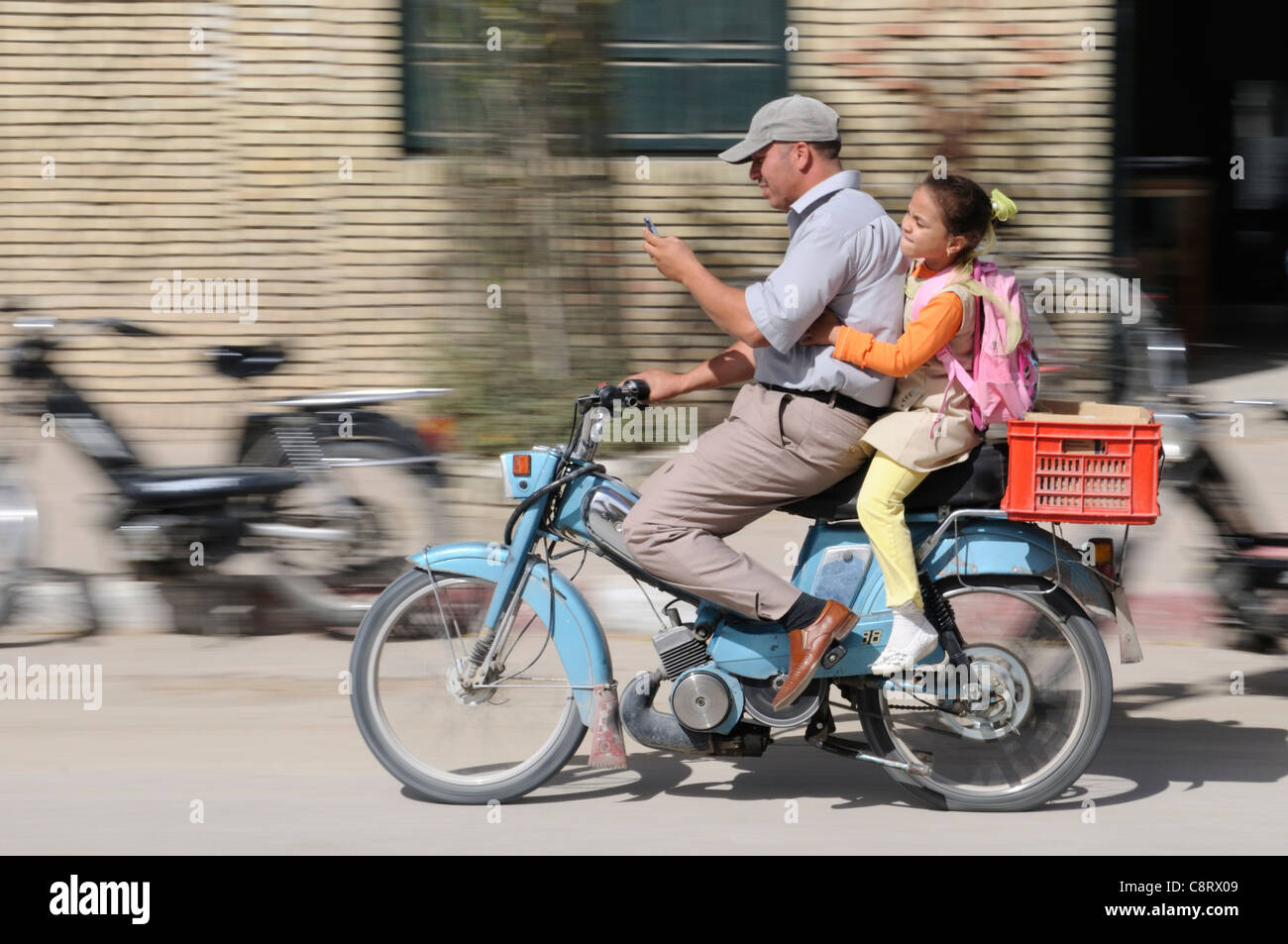 Afrika, Tunesien, Tozeur. Tunesischen Vater und Tochter auf Moped mit Handy. Stockfoto