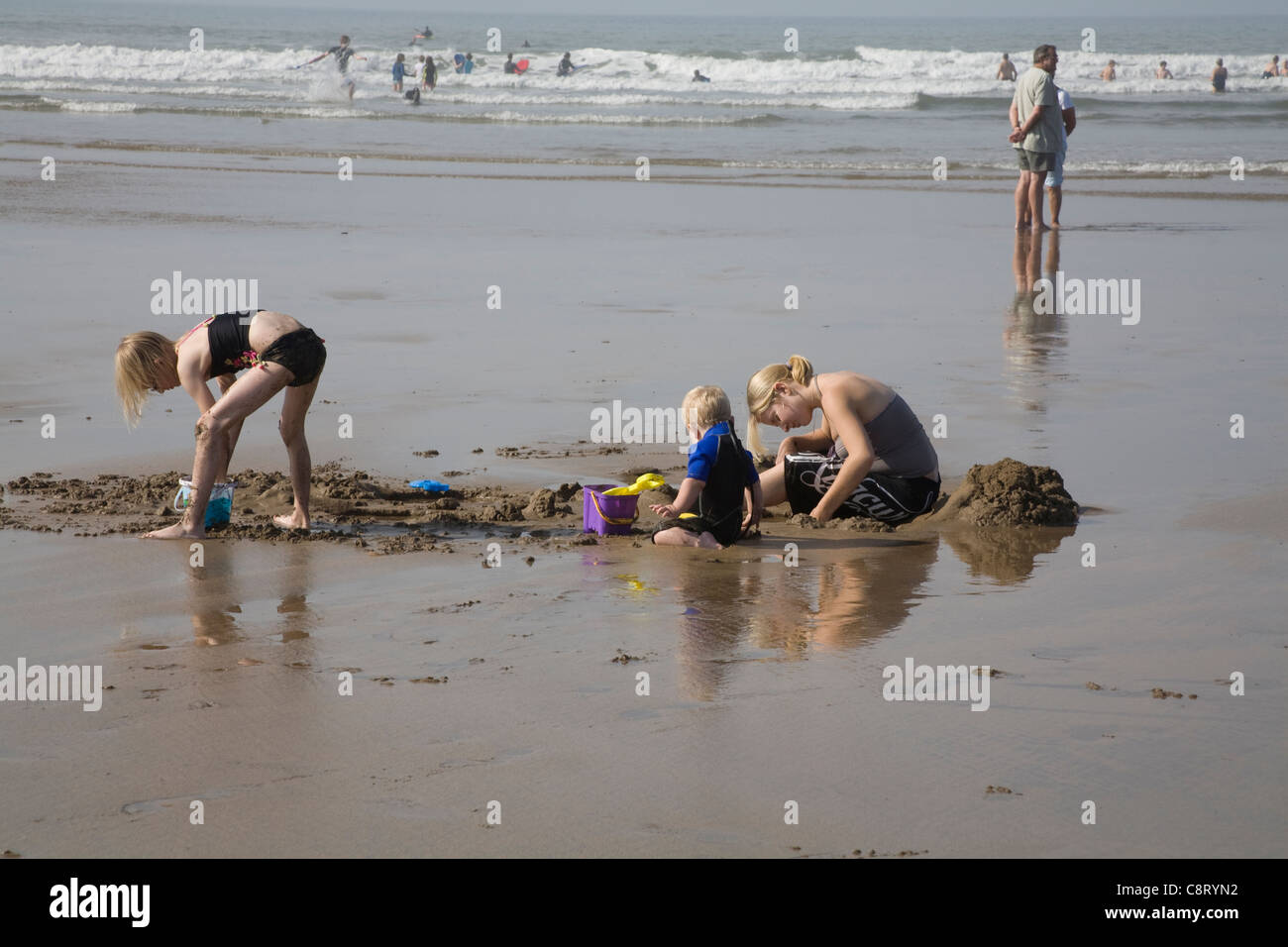 Bude Cornwall England September Mutter mit Sohn tragen Neoprenanzug und Tochter graben im Sand am Strand Stockfoto