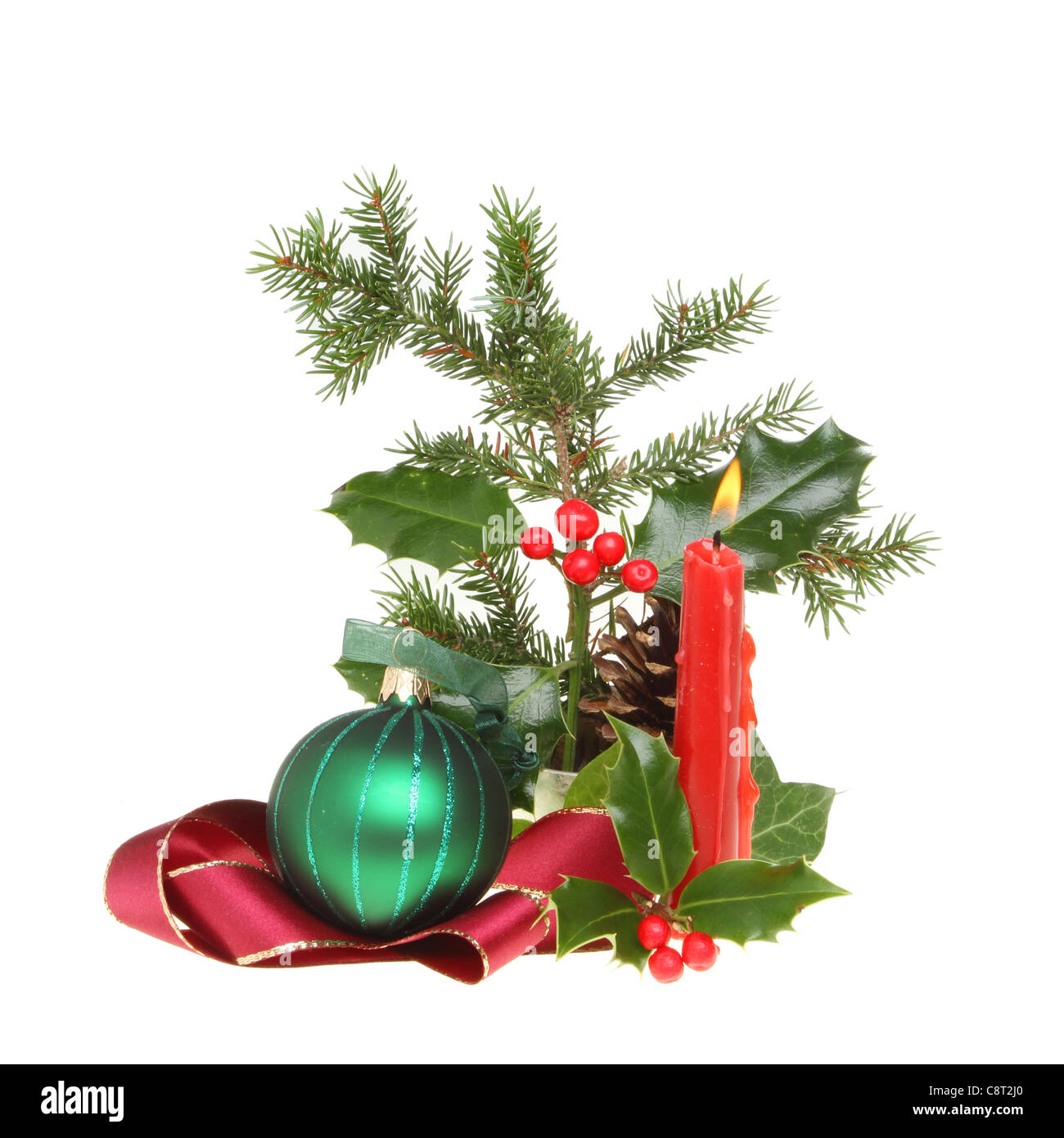 Weihnachten Tischdekoration von saisonalen Laub, brennende Kerze, Band und Christbaumkugel isoliert gegen weiß Stockfoto