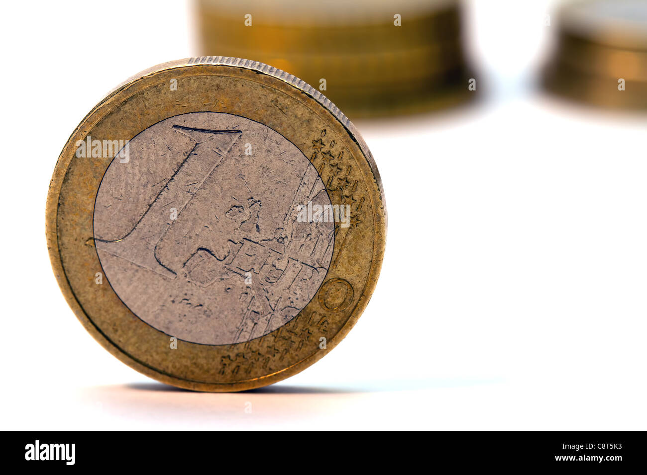 1 Euromünze isoliert auf weiss mit Euro-Münzen im Hintergrund. Makroaufnahme. Stockfoto