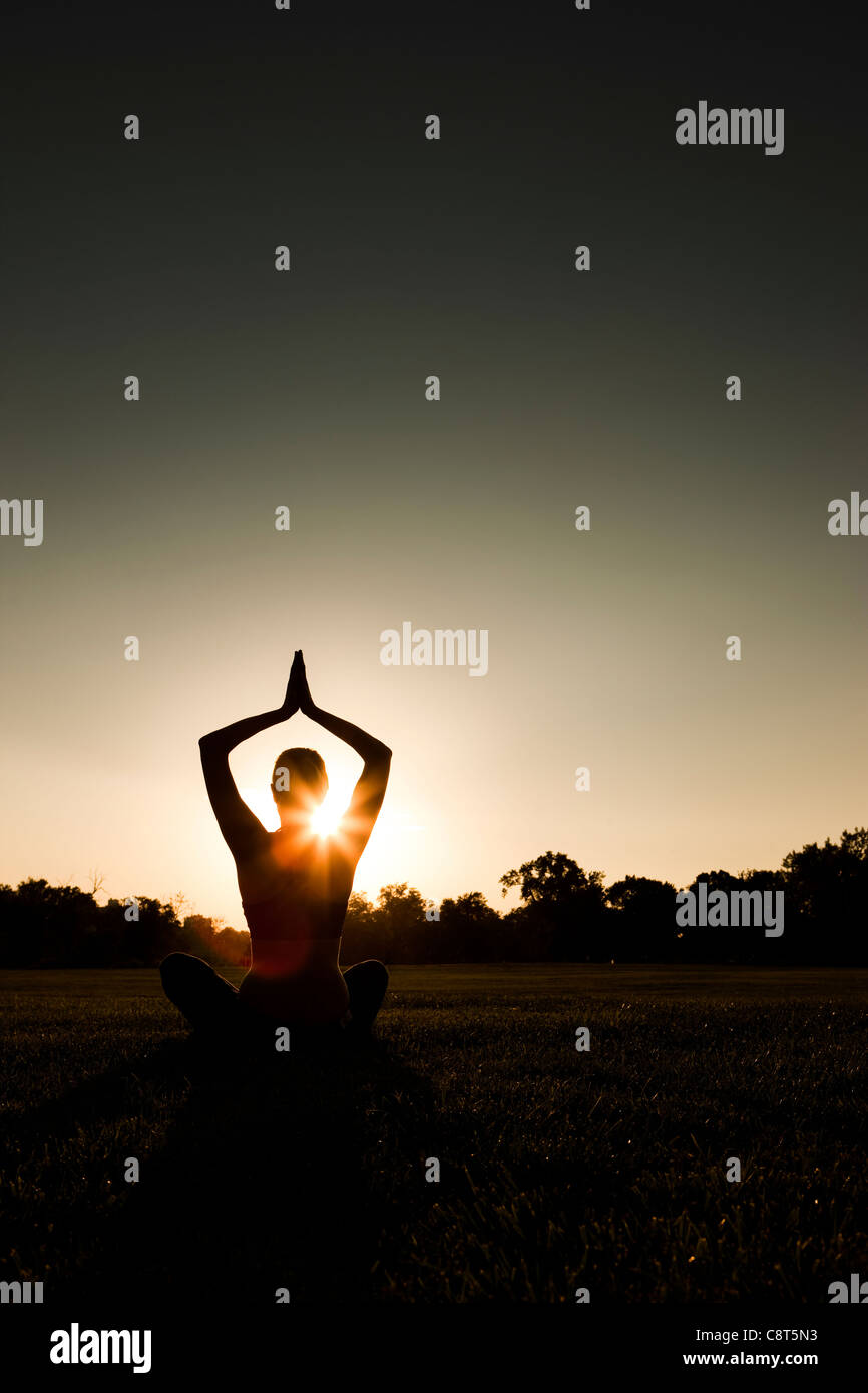 Kaukasische Frau praktizieren Yoga bei Sonnenuntergang Stockfoto