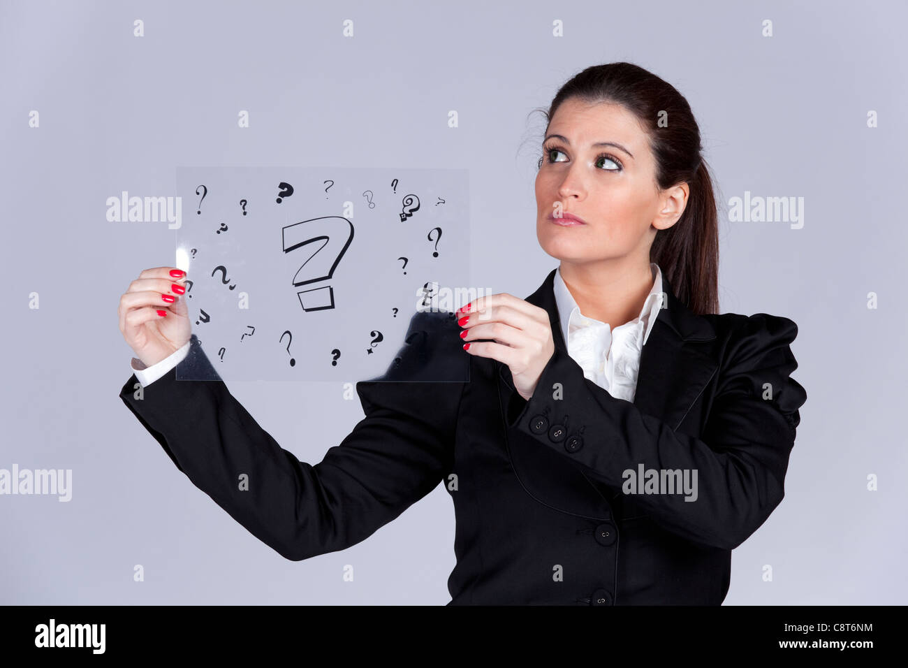 Geschäftsfrau hält ein Acetat mit vielen Fragezeichen Stockfoto