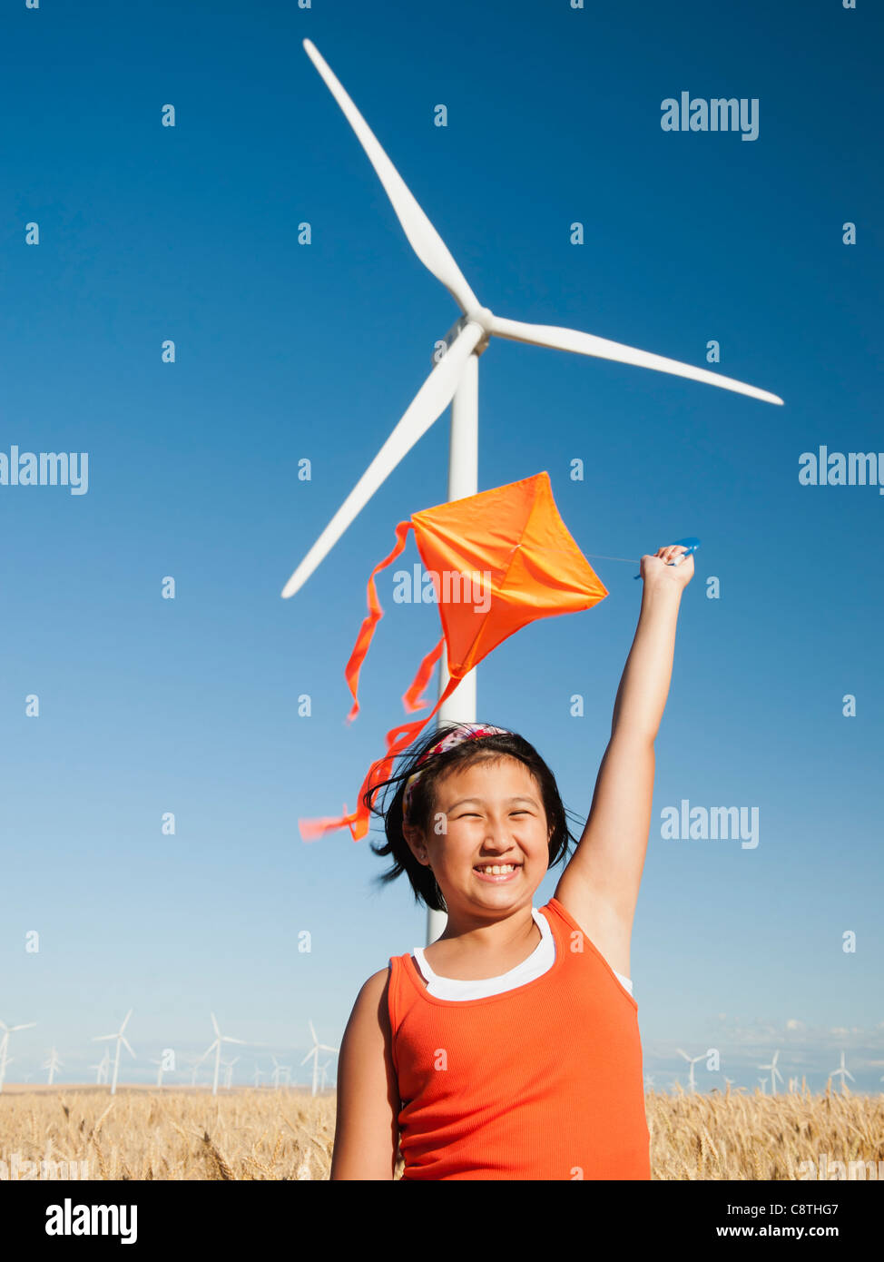 USA, Oregon, Wasco, Mädchen 10-11) spielen mit Drachen im Weizenfeld, wind Turbine im Hintergrund Stockfoto