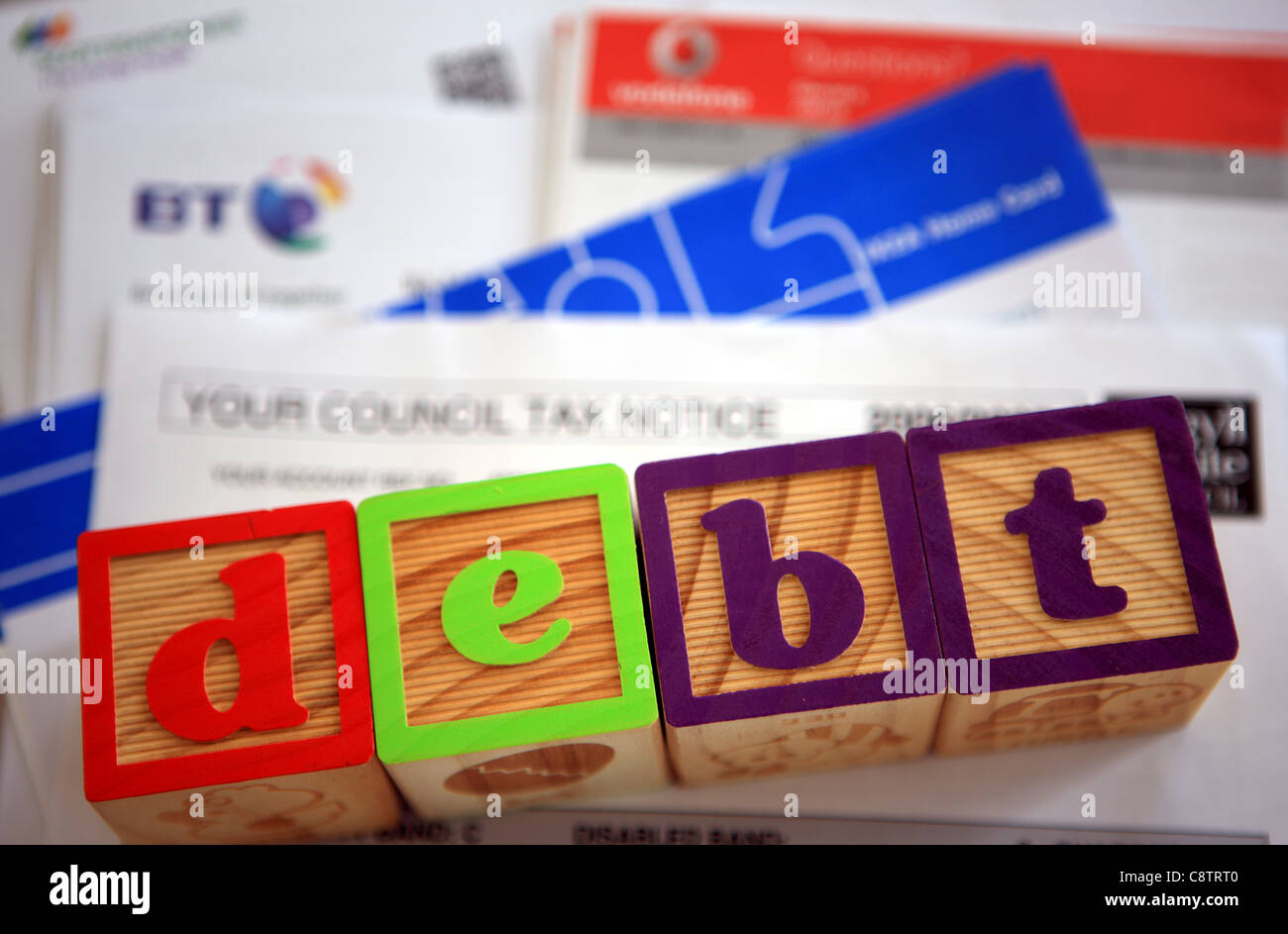 Haufen von Rechnungen mit dem Wort Schulden dargelegt in Bausteine auf Ihnen Stockfoto